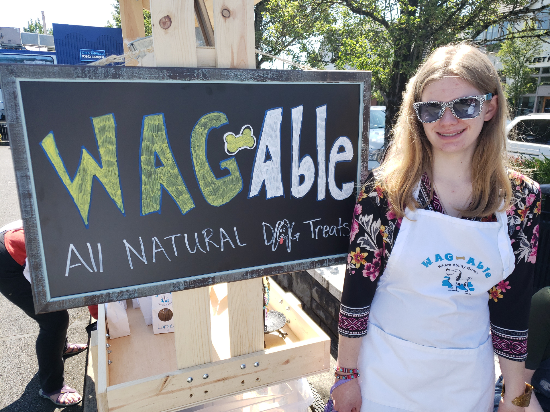 Intern Kelsey with the W.A.G. Able sign at a Lake Oswego market